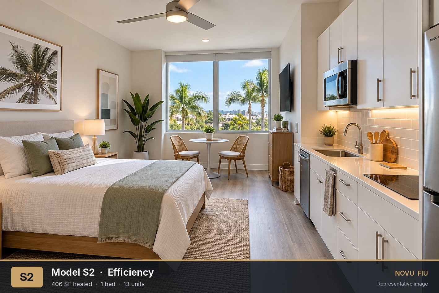 Open-plan bedroom and kitchenette with plank flooring, white cabinetry, and a large window.